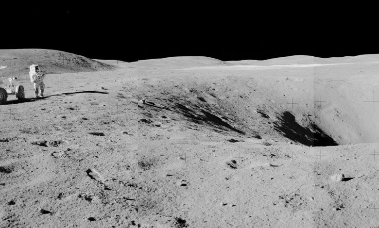 Uma foto em ângulo aberto de uma cratera na lua, com um astronauta e um veículo lunar ao lado