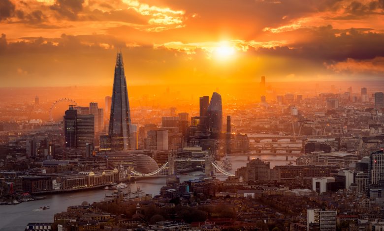 Um lindo pôr do sol atrás do horizonte de Londres com a Tower Bridge, o Rio Tâmisa e os arranha-céus corporativos.