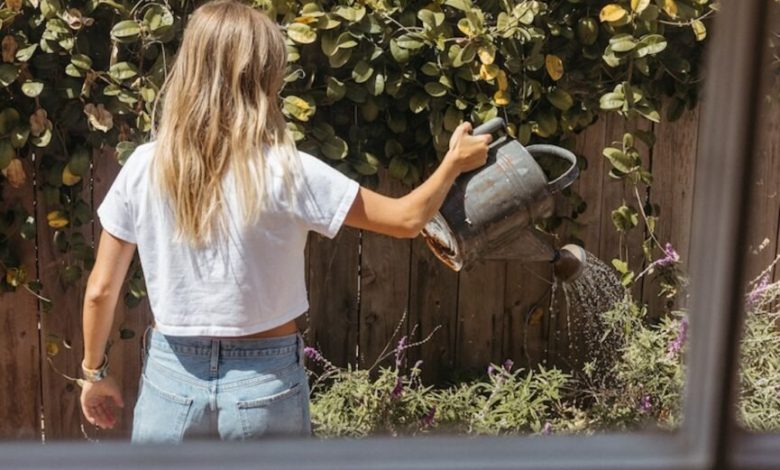 Mulher regando jardim usando jeans outono de 2024.