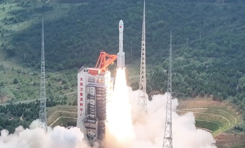 Um grande foguete sendo lançado de uma torre de andaimes na selva